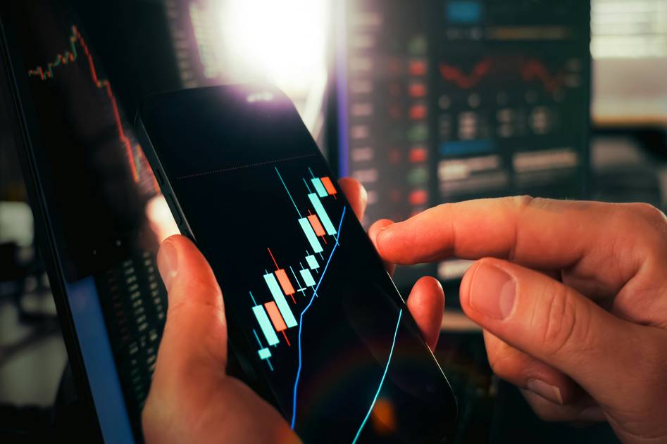 Trader reviewing backtest charts on monitor with candlestick graphs
